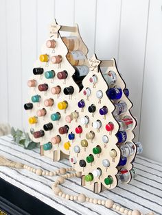 two wooden christmas trees are sitting on top of a striped tablecloth with beaded beads