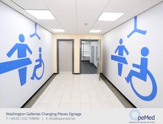 an empty hallway with blue and white signs on the walls, along with urinals