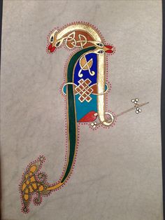 an intricately decorated letter e on a piece of parchment paper with gold and green trim