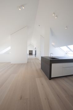 an empty room with wooden floors and white walls, is seen in this image from the side