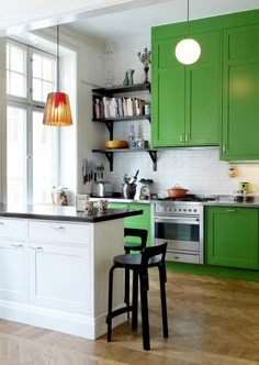 a kitchen with green cabinets and white counter tops, two stools in front of the island