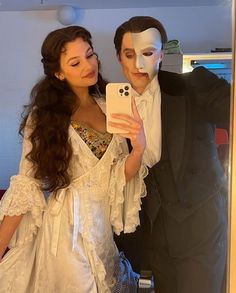 a man in a tuxedo taking a selfie with a woman wearing a mask