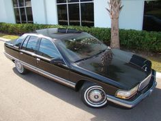 a brown and black car parked in front of a building with palm trees on it