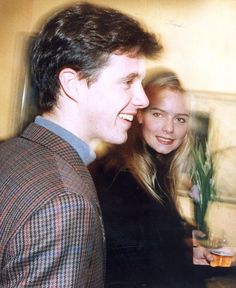 a man and woman standing next to each other with drinks in their hands, smiling