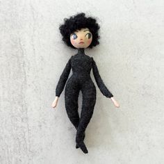 a doll with black hair laying on top of a white floor next to a wall