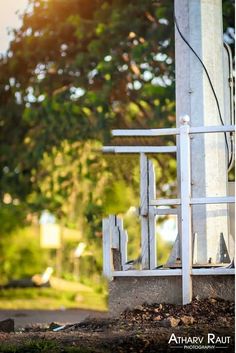 an old white wooden chair sitting on the side of a building next to a tree