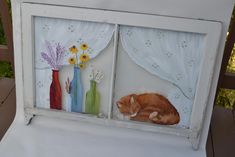 an orange cat laying on top of a white table next to vases and flowers