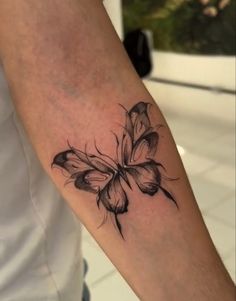 a black and white photo of a butterfly tattoo on the left arm, with wings spread out