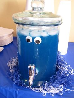 a blue table topped with a glass jar filled with liquid and googly eyeballs