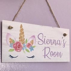 a wooden sign hanging on the wall that says, sienna's room with unicorn ears and flowers