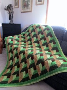 a green and brown blanket sitting on top of a couch