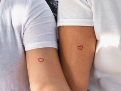 two people with small tattoos on their arms, one is holding the other's arm