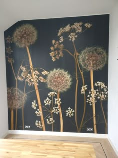 the wall is painted with dandelions and other plants on it, as well as a wooden floor