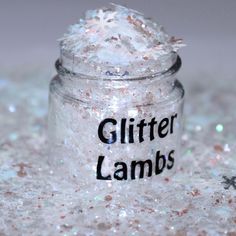 glitter lambs in a glass jar on top of snow flakes with the words glitter lambs written on it