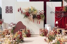 an outdoor ceremony with red and white flowers on the wall, decorated with greenery