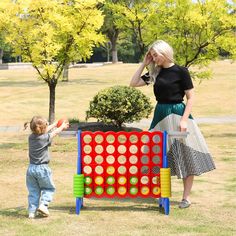 a woman standing next to a child near a giant game