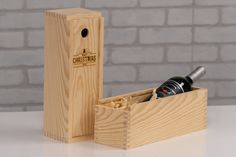 a bottle of wine in a wooden box on a table next to a brick wall