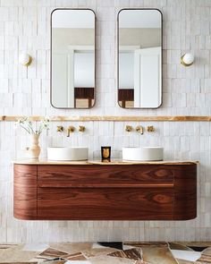 a bathroom with two sinks and mirrors on the wall next to each other in front of a tiled wall