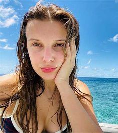 a woman with wet hair sitting on a boat in the ocean looking at the camera