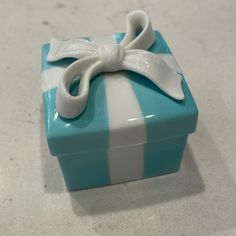 a small blue and white box with a bow on it's lid sitting on a table