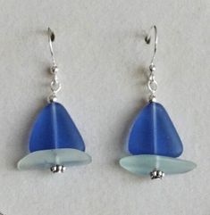 two blue and white glass earrings hanging from silver earwires on a white surface