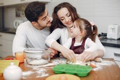 a man, woman and child are making dough in the kitchen with flour on the table