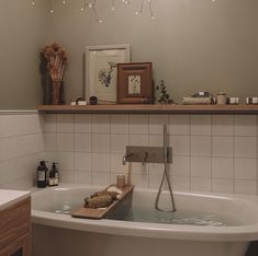 a bathroom with a bathtub, sink and shelves on the wall above it that have candles in them