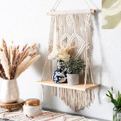 a macrame hanging on the wall next to potted plants and vases