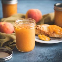 a glass jar filled with liquid next to some peaches and bread on a plate