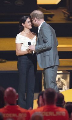 a man and woman standing next to each other in front of an audience holding microphones