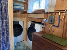 a washer and dryer in a small room with wood paneling on the walls