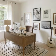 a desk with a guitar, lamp and pictures on the wall