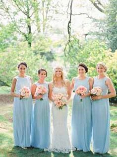 the bride and her bridesmaids posing for a photo in front of some trees