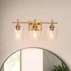 three light bathroom fixture with clear glass shades and brass finish, in a modern style