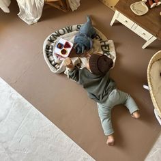 a small child laying on the floor next to a stuffed animal and some toys in a basket