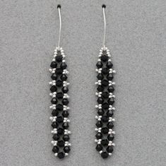 pair of black and white beaded earrings on grey background with space for text or image