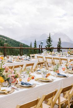 an outdoor table set up with flowers and plates