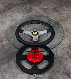 a glass table with a steering wheel on top of it and a red object in the middle