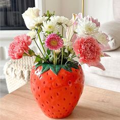 a strawberry shaped vase filled with flowers on top of a table