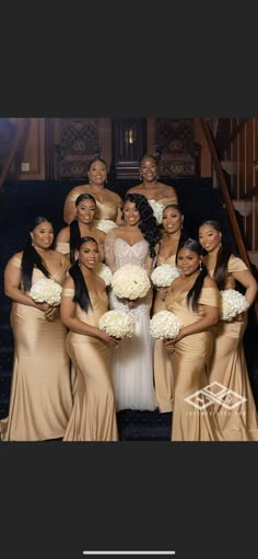 a group of women standing next to each other in front of a stair case holding bouquets