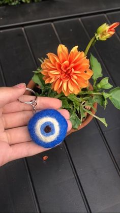 a hand holding a flower pot with an evil eye keychain hanging from it