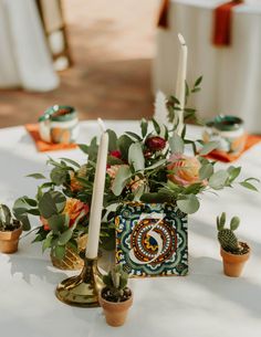 a table topped with candles and flowers on top of a white cloth covered tablecloth