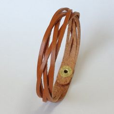 a brown leather bracelet with gold buttons on the clasp and an eye in the center