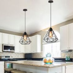 three lights hanging over a kitchen island with stools in front of the counter top