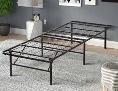 a metal bed frame sitting on top of a rug in a living room next to a plant