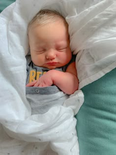 a baby sleeping in a blanket on top of a bed