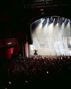 an audience at a concert with their hands up in the air as they perform on stage