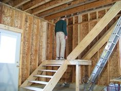 a man standing on top of a stair case in a room under construction with wooden walls