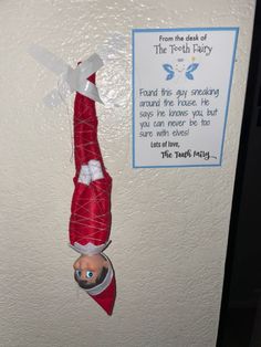 an elf hanging from the side of a door with a sign above it that reads, from the desk of the tooth fairy