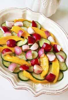 a white bowl filled with cucumbers and yellow peppers